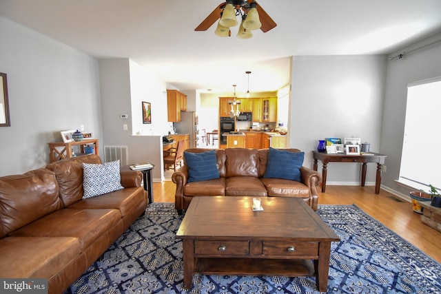 living room featuring light wood-style flooring, a ceiling fan, and baseboards