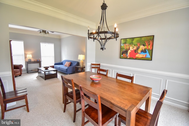 dining space with light carpet, a decorative wall, crown molding, and a wainscoted wall