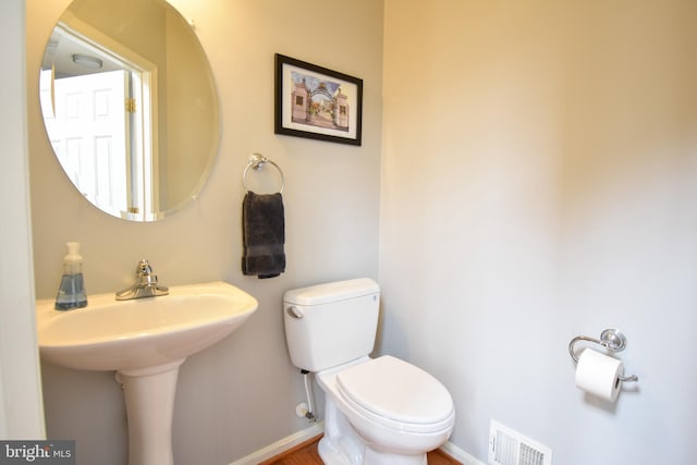 half bath featuring visible vents, toilet, and baseboards