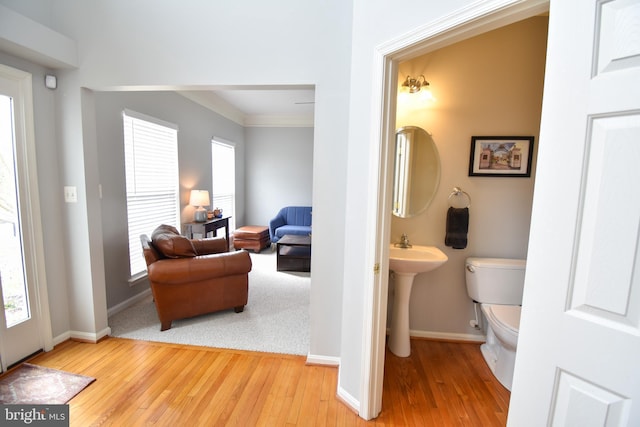 half bathroom featuring hardwood / wood-style floors, crown molding, toilet, and baseboards