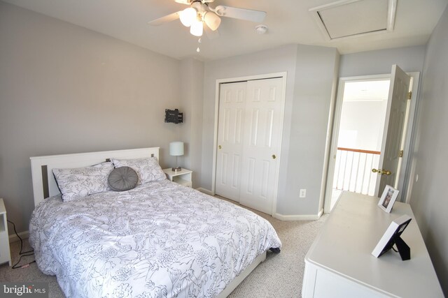 bedroom featuring light colored carpet, ceiling fan, and a closet