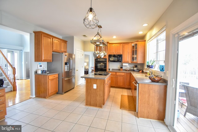 kitchen featuring pendant lighting, black appliances, light tile patterned floors, a center island, and sink