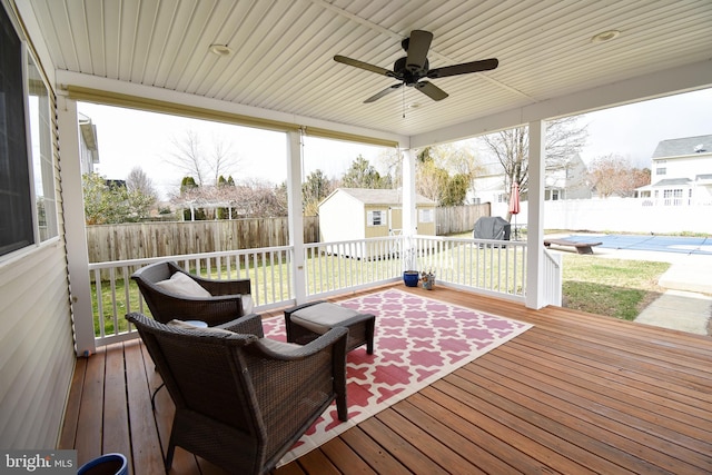 wooden terrace featuring ceiling fan, an outbuilding, a fenced backyard, and a storage shed