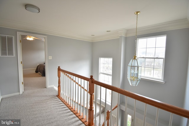 corridor featuring visible vents, an upstairs landing, carpet floors, and ornamental molding