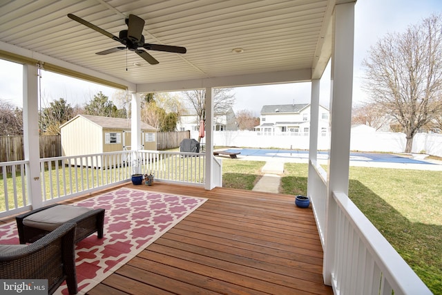 wooden terrace featuring a yard, ceiling fan, and a storage shed