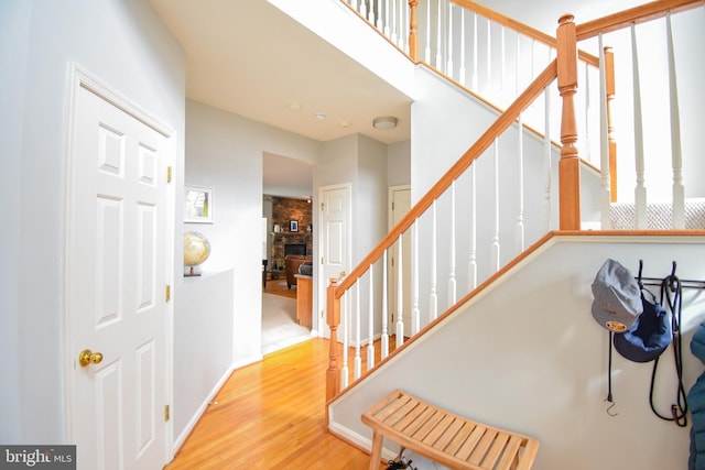 stairs featuring a stone fireplace, wood finished floors, and baseboards