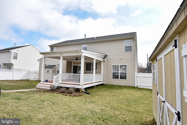 rear view of house featuring ceiling fan, a lawn, a deck, and fence