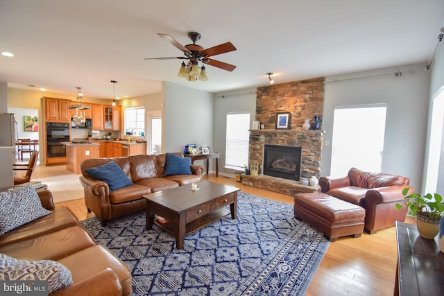 living room with a fireplace, light hardwood / wood-style flooring, and ceiling fan