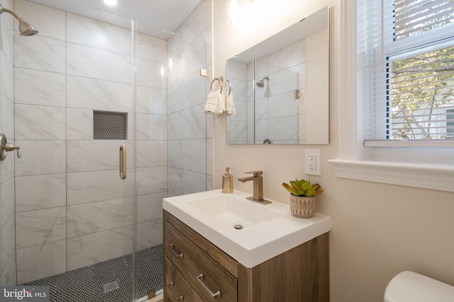 bathroom with an enclosed shower, vanity, and toilet