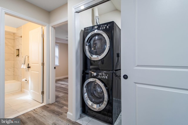 washroom with wood-type flooring and stacked washer and dryer