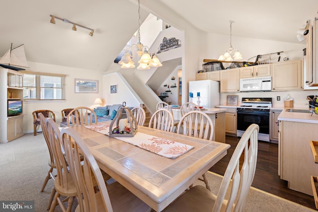 dining space featuring track lighting, a notable chandelier, dark wood-type flooring, and vaulted ceiling