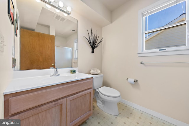 bathroom featuring a shower with shower door, vanity, and toilet