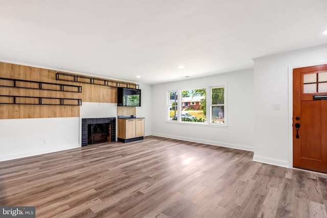 unfurnished living room featuring light hardwood / wood-style flooring and a brick fireplace