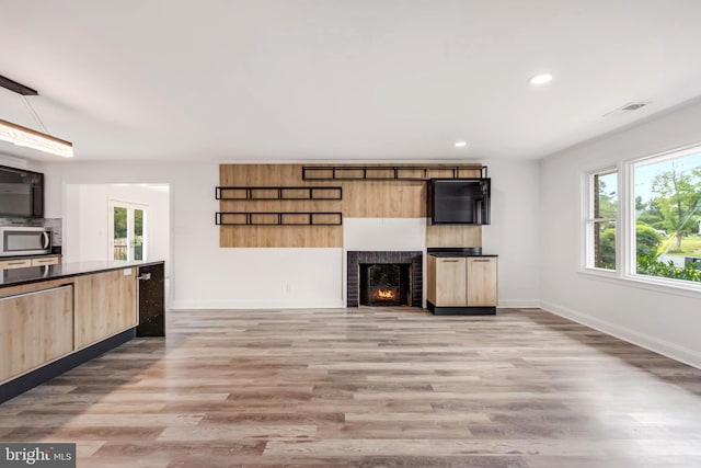 unfurnished living room with a brick fireplace and light wood-type flooring