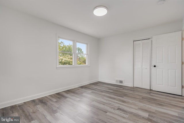 unfurnished bedroom with light wood-type flooring and a closet