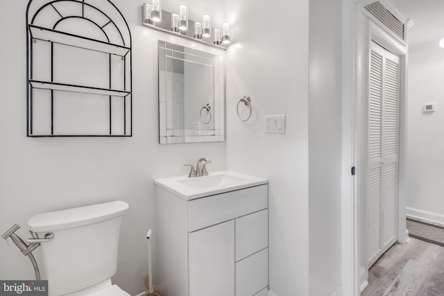 bathroom with wood-type flooring, vanity, and toilet