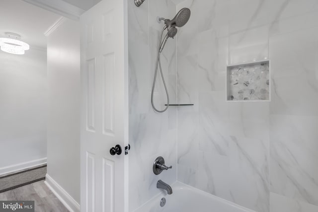 bathroom featuring wood-type flooring, tiled shower / bath, and ornamental molding