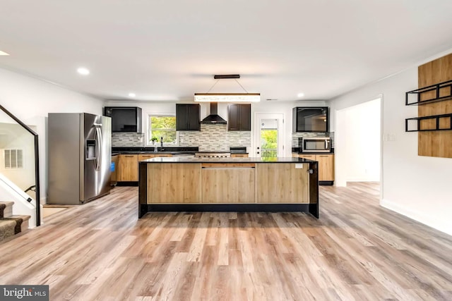 kitchen featuring light hardwood / wood-style floors, a center island, tasteful backsplash, wall chimney exhaust hood, and stainless steel appliances