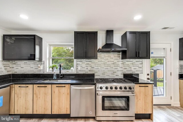 kitchen with light hardwood / wood-style floors, light brown cabinets, stainless steel appliances, sink, and wall chimney range hood