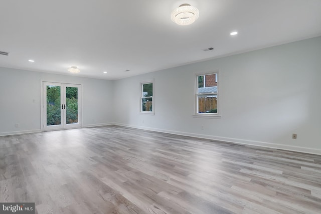 spare room featuring light wood-type flooring, a healthy amount of sunlight, and french doors