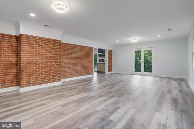 unfurnished living room with light hardwood / wood-style floors and brick wall