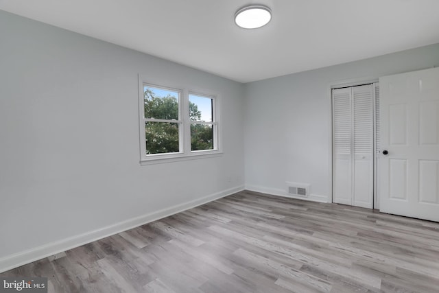 unfurnished bedroom with light wood-type flooring and a closet