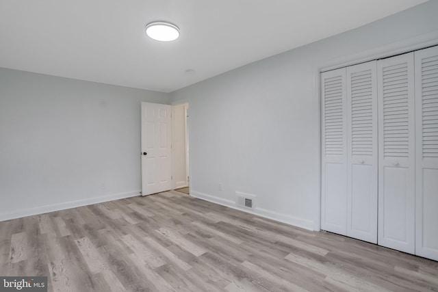 unfurnished bedroom with light hardwood / wood-style flooring and a closet