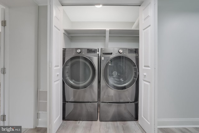 clothes washing area featuring light hardwood / wood-style floors and washing machine and clothes dryer