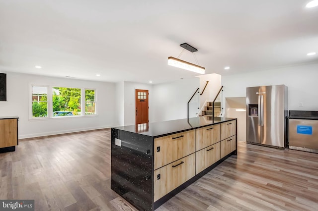 kitchen with stainless steel fridge with ice dispenser, a kitchen island, hardwood / wood-style floors, light brown cabinetry, and stainless steel fridge