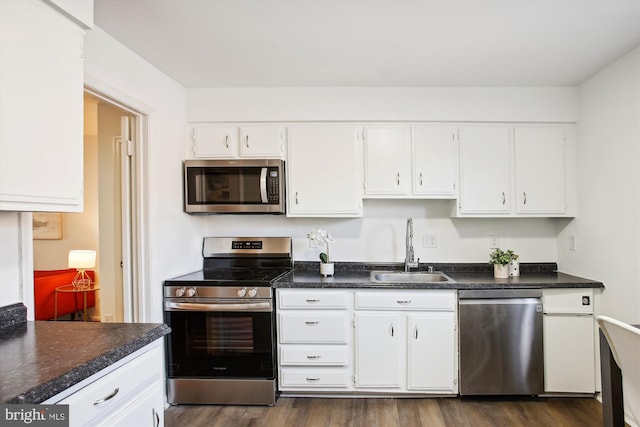 kitchen with dark wood-type flooring, white cabinets, appliances with stainless steel finishes, and sink