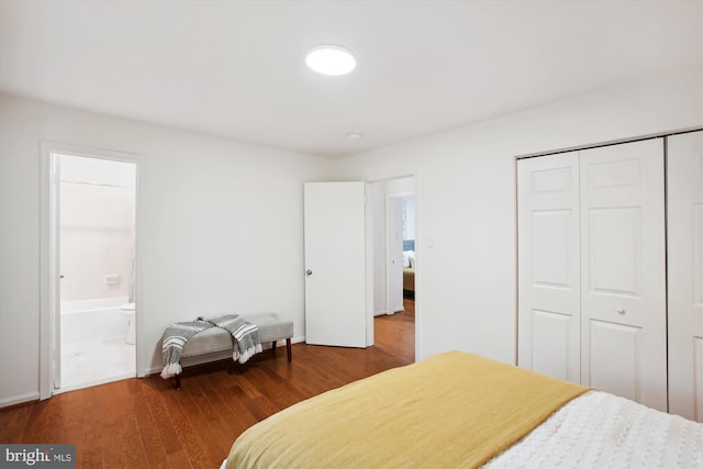 bedroom with ensuite bath, dark wood-type flooring, and a closet