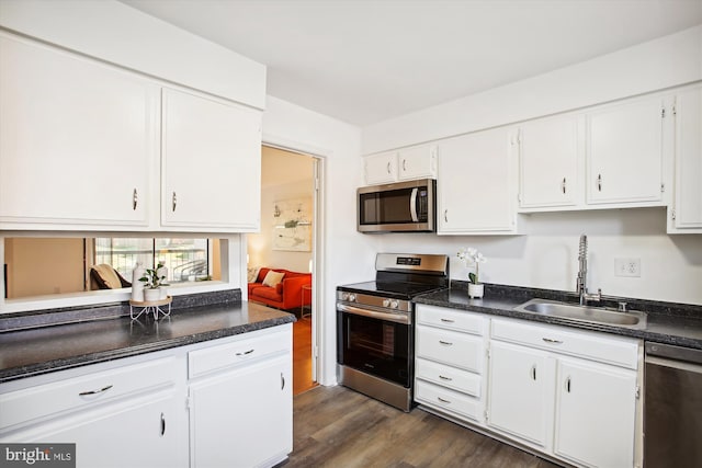 kitchen with dark wood-type flooring, stainless steel appliances, white cabinetry, and sink