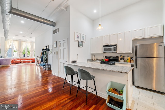 kitchen with light stone counters, stainless steel appliances, white cabinets, and light hardwood / wood-style floors