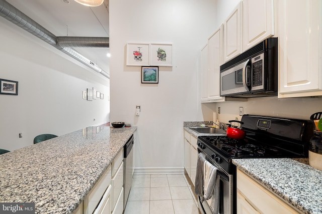 kitchen with light tile patterned floors, light stone counters, sink, and appliances with stainless steel finishes