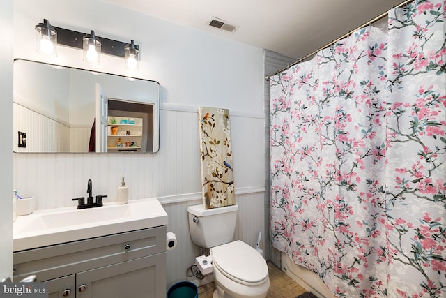 bathroom featuring walk in shower, toilet, and vanity