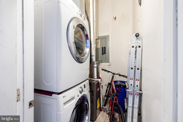 laundry area featuring electric panel, stacked washer / drying machine, and tile patterned flooring