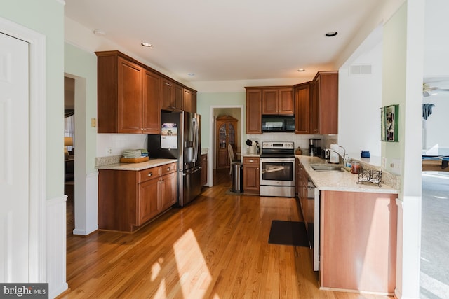 kitchen with ceiling fan, light stone countertops, backsplash, appliances with stainless steel finishes, and hardwood / wood-style flooring