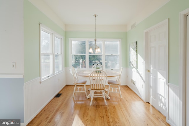 dining space with light hardwood / wood-style floors and an inviting chandelier