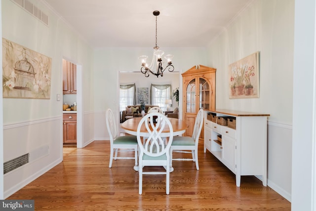 dining room featuring hardwood / wood-style flooring, an inviting chandelier, and ornamental molding