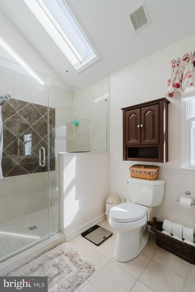 bathroom featuring tile patterned floors, toilet, a shower with shower door, and lofted ceiling with skylight