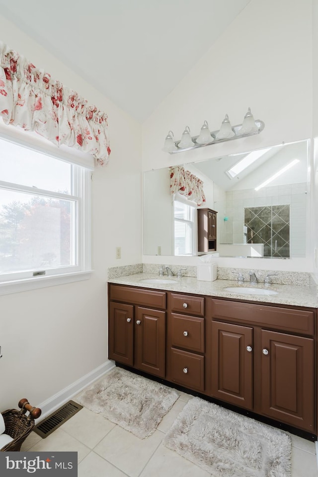 bathroom featuring vaulted ceiling with skylight, vanity, and tile patterned flooring