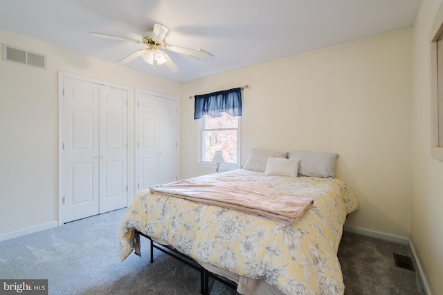 bedroom featuring dark colored carpet, two closets, and ceiling fan