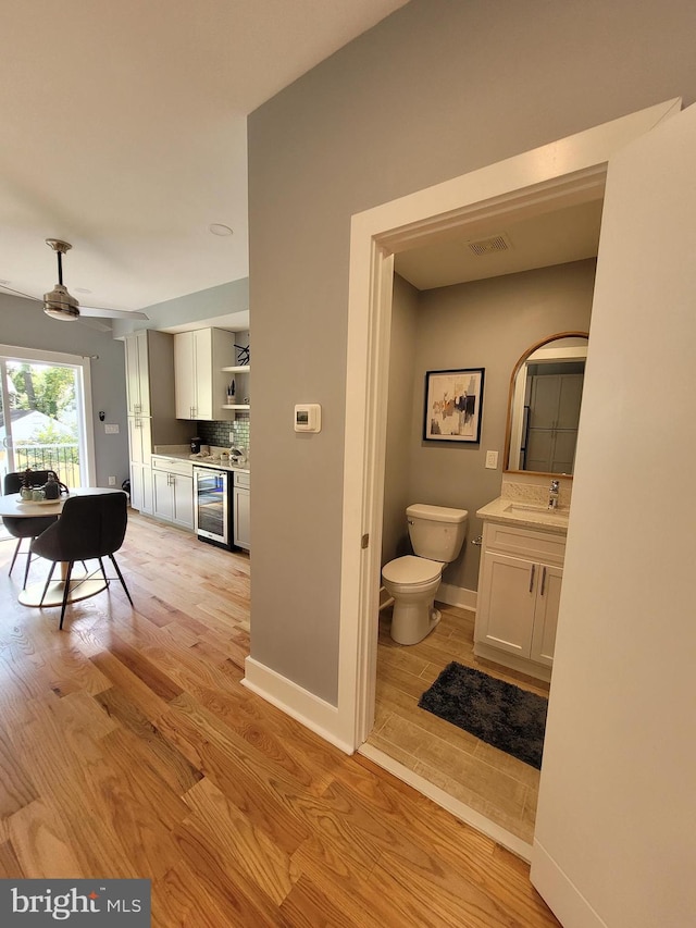 interior space featuring beverage cooler, light hardwood / wood-style flooring, and sink