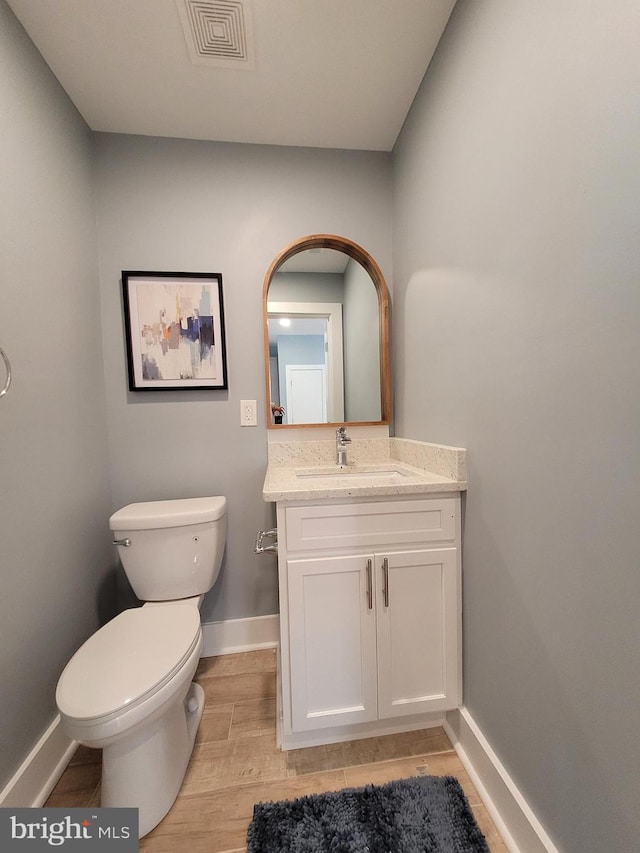 bathroom with vanity, toilet, and hardwood / wood-style flooring