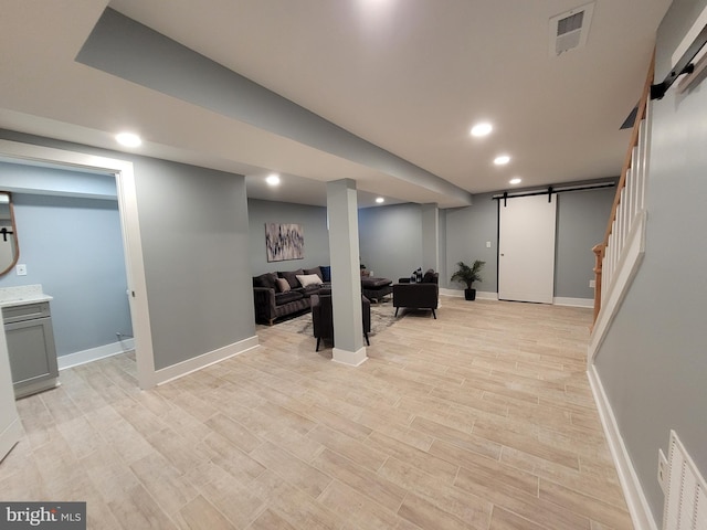 basement featuring light wood-type flooring and a barn door