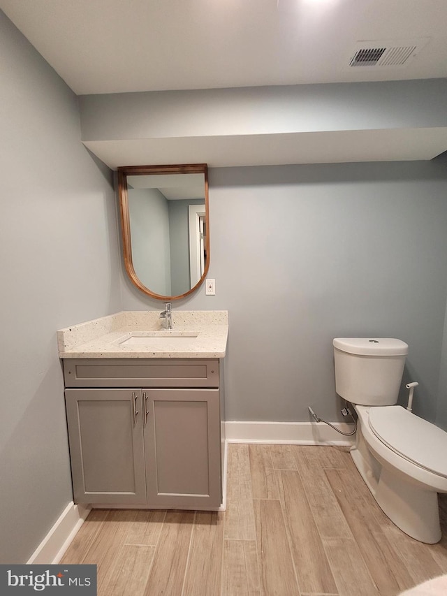 bathroom featuring vanity, hardwood / wood-style flooring, and toilet