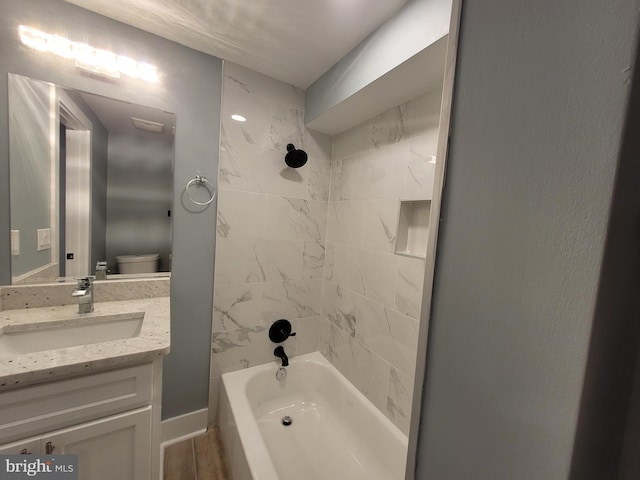 full bathroom featuring vanity, hardwood / wood-style flooring, tiled shower / bath, and toilet