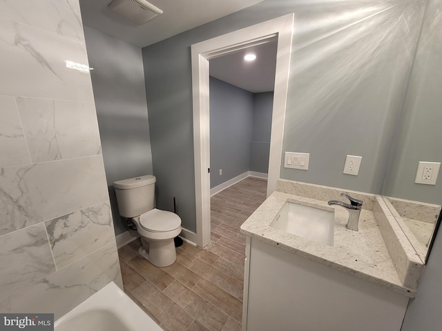 bathroom featuring a washtub, vanity, toilet, and hardwood / wood-style flooring