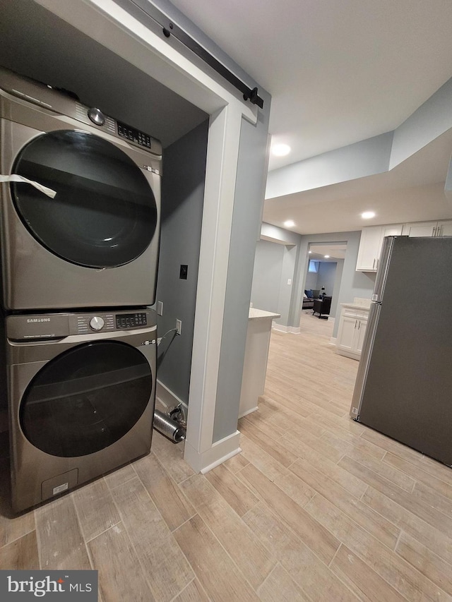 washroom with stacked washer / drying machine and light hardwood / wood-style flooring