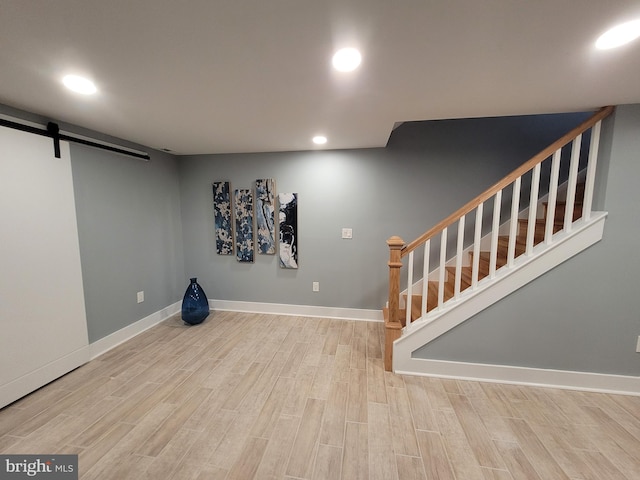 basement featuring wood-type flooring and a barn door